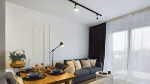 Uma sala de estar moderna com uma mesa de jantar, sofá e janelas amplas.