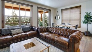 Un salón espacioso con un amplio sofá de cuero, una mesa de centro de madera y un comedor con mesa y sillas.