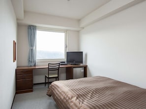 A small, clean room with a single bed, a desk with a computer, a chair, and a window with a curtain. - Komoro Grand Castle Hotel (Komoro)