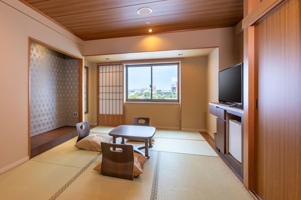 A traditional Japanese-style room with tatami flooring, a low table, and a television.