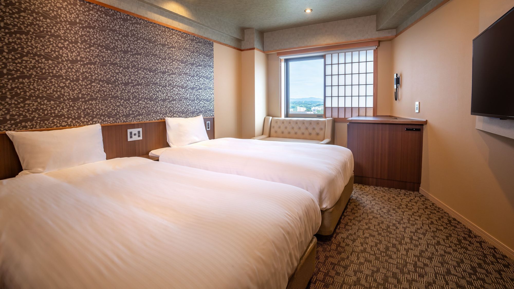 A hotel room with two beds, a window with a view, a flat-screen TV, and a minibar.