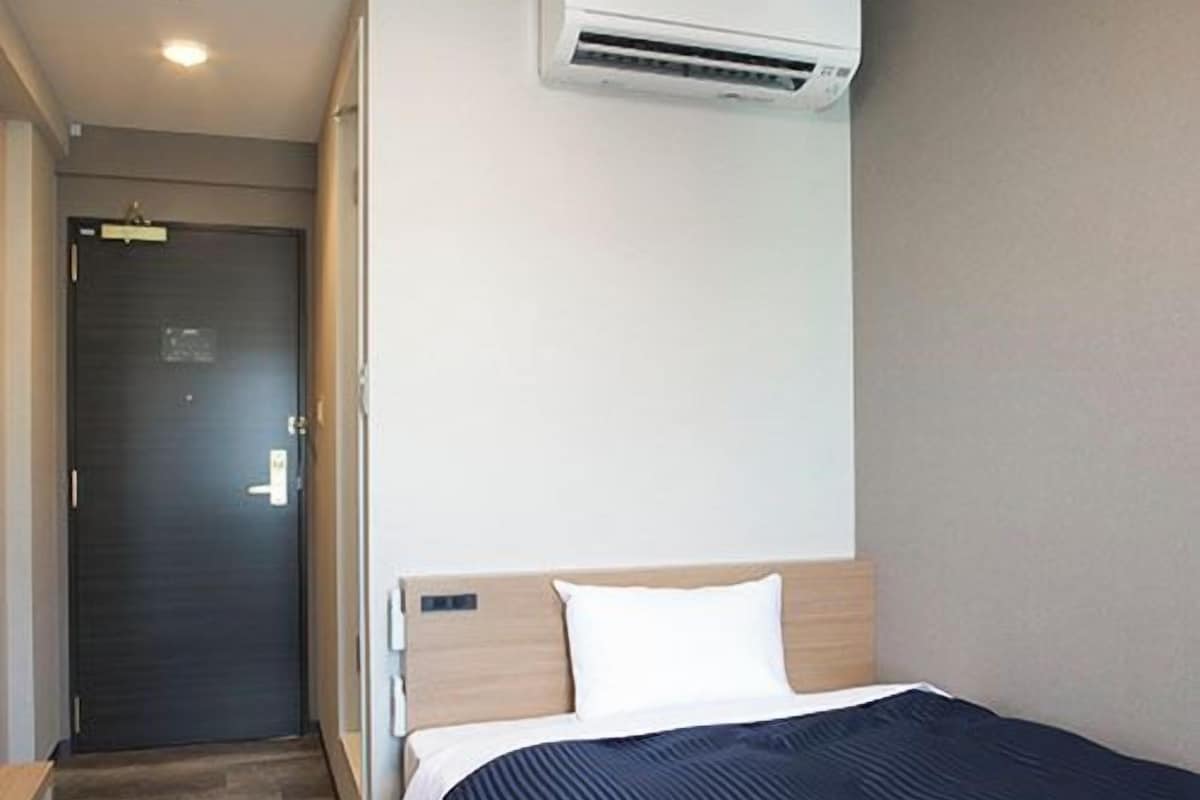 Une chambre d’hôtel équipée d’un lit, d’un bureau, d’une armoire et d’un appareil de climatisation.