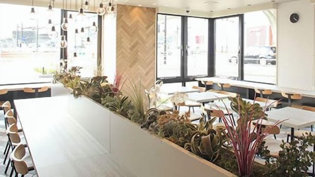 A modern interior with a long counter, hanging pendant lights, and a herringbone-patterned wall.