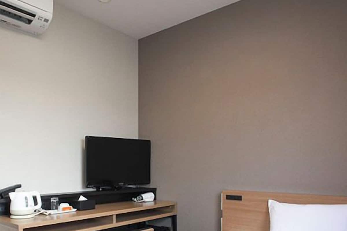 Una habitación de hotel con una cama, un televisor sobre un escritorio y una cafetera.