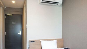 Een hotelkamer met een bed, een bureau, een kledingkast en een airconditioning.