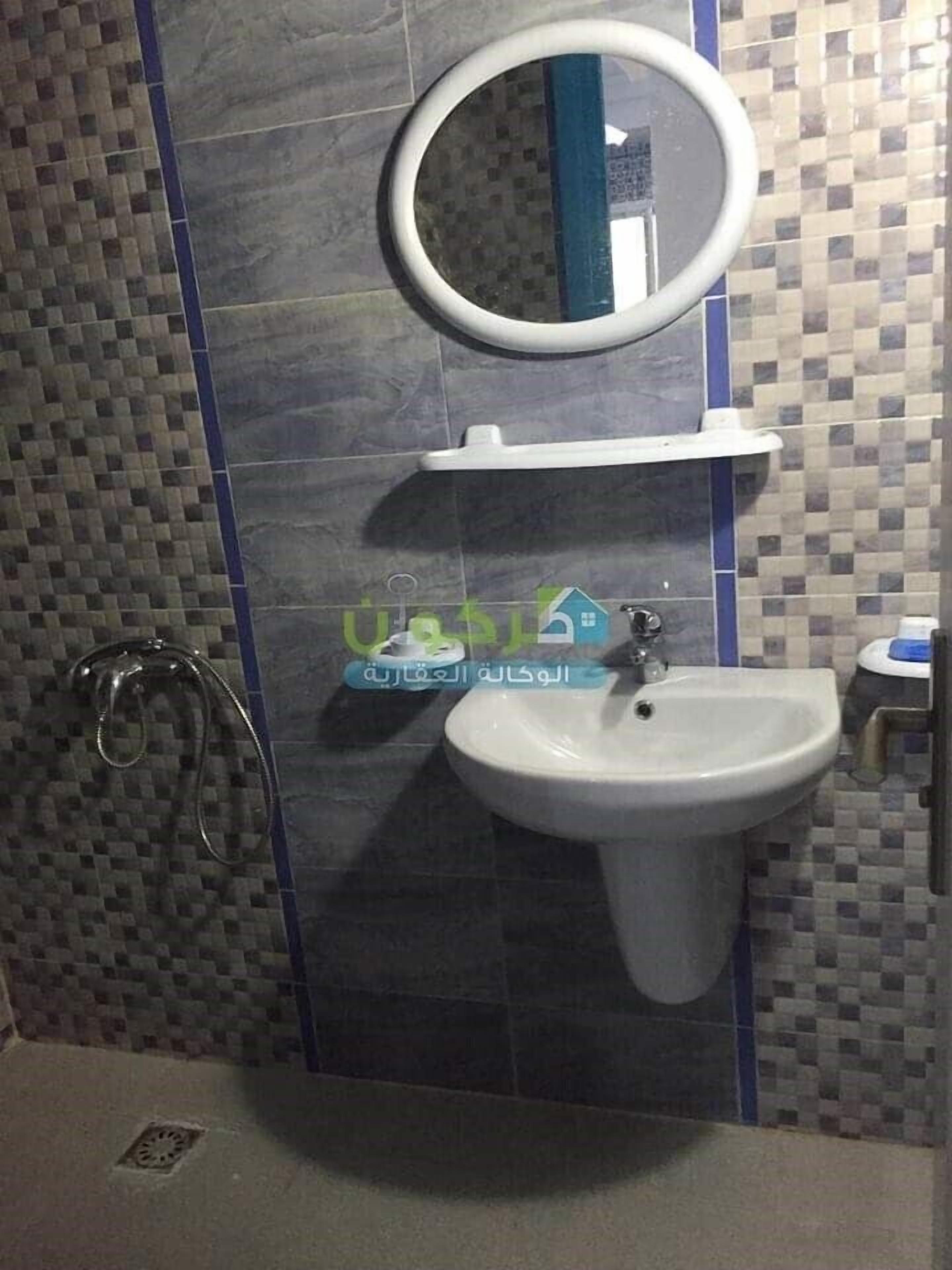 Un bagno con un lavandino bianco, uno specchio sopra e una zona doccia con soffione.