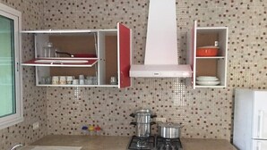 Une cuisine avec un mur recouvert de carreaux, une cuisinière, des placards et un réfrigérateur.
