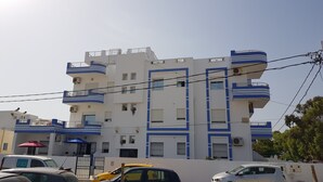 Un immeuble à plusieurs étages doté de balcons, de climatiseurs et d’une entrée sécurisée par un portail.