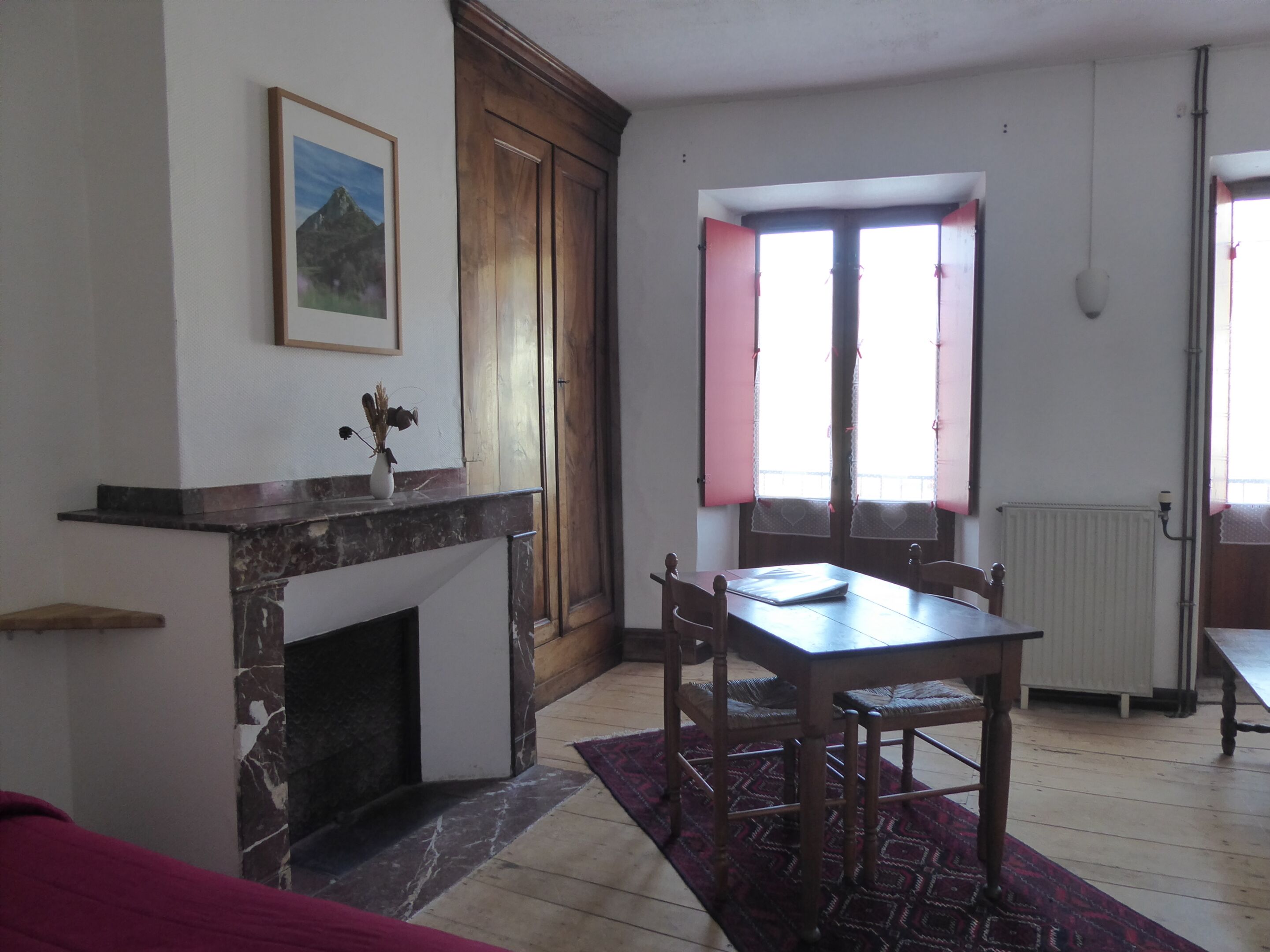A dining area with a wooden table and chairs, a fireplace, and a window with curtains.