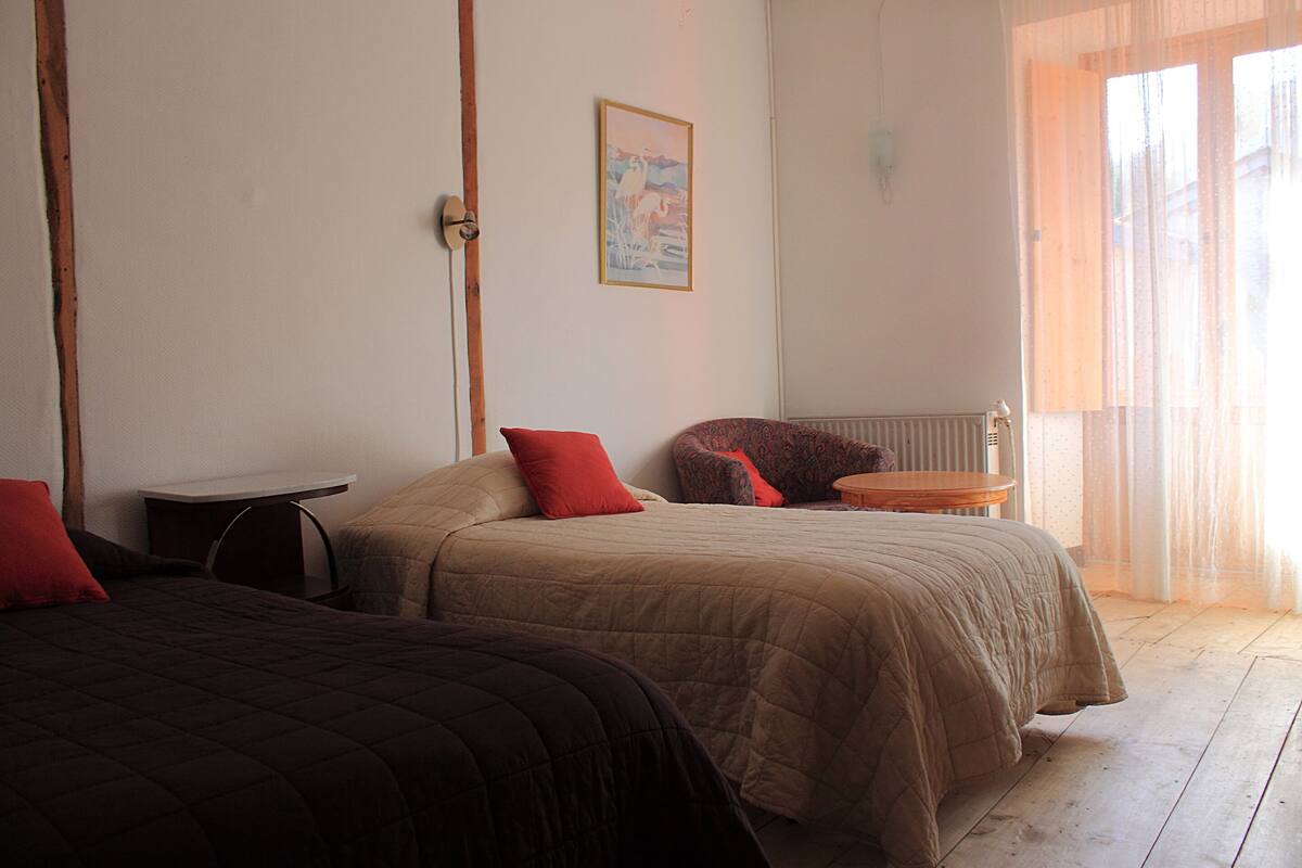 A room with two beds, a small table, and a chair.