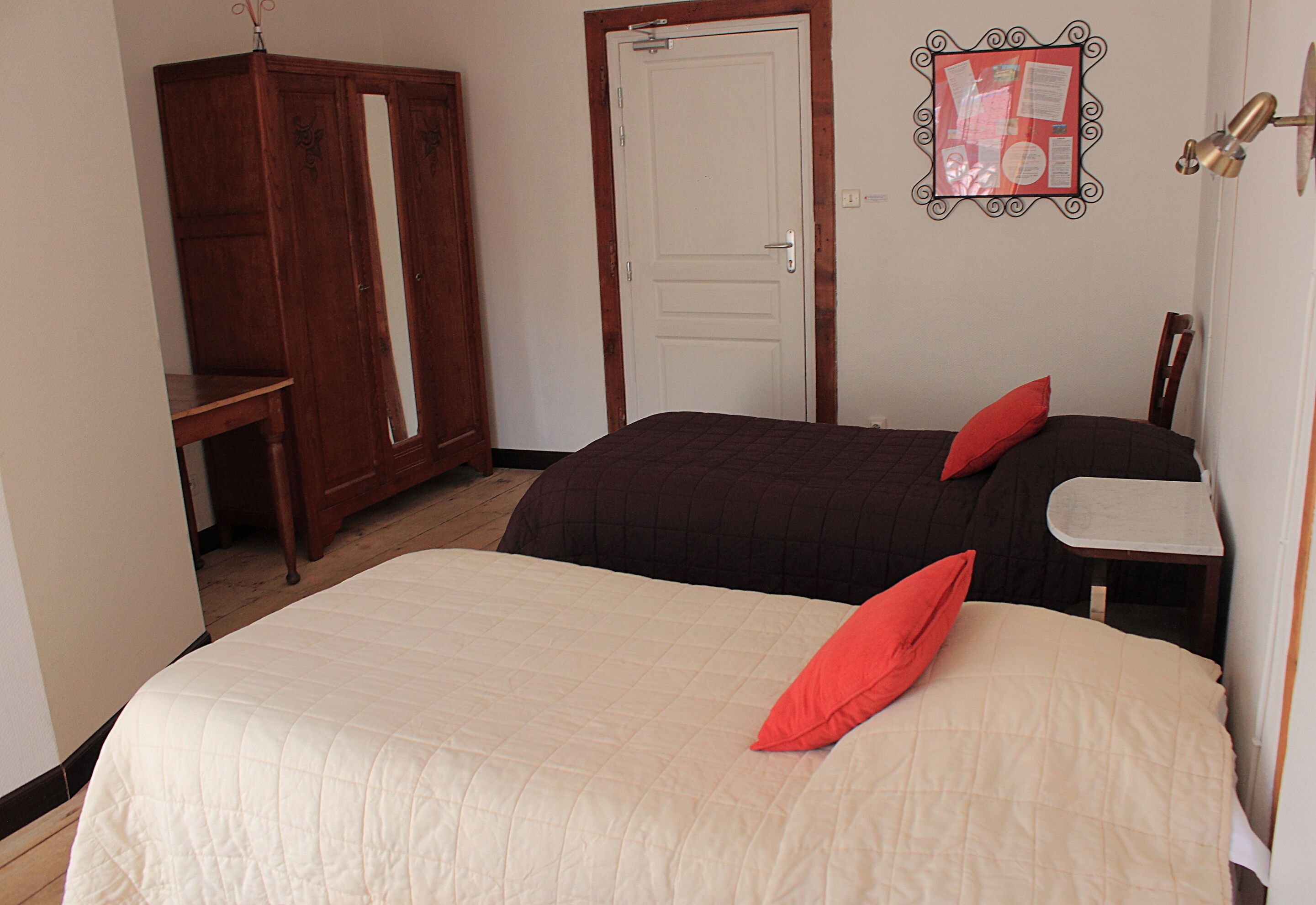 A bedroom with two beds, a wardrobe, and a desk.
