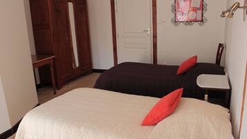 A bedroom with two beds, a wardrobe, and a desk.