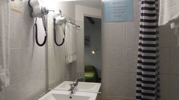 Ein Badezimmer mit Waschbecken, Spiegel und zwei an der Wand befestigten Haartrocknern.
