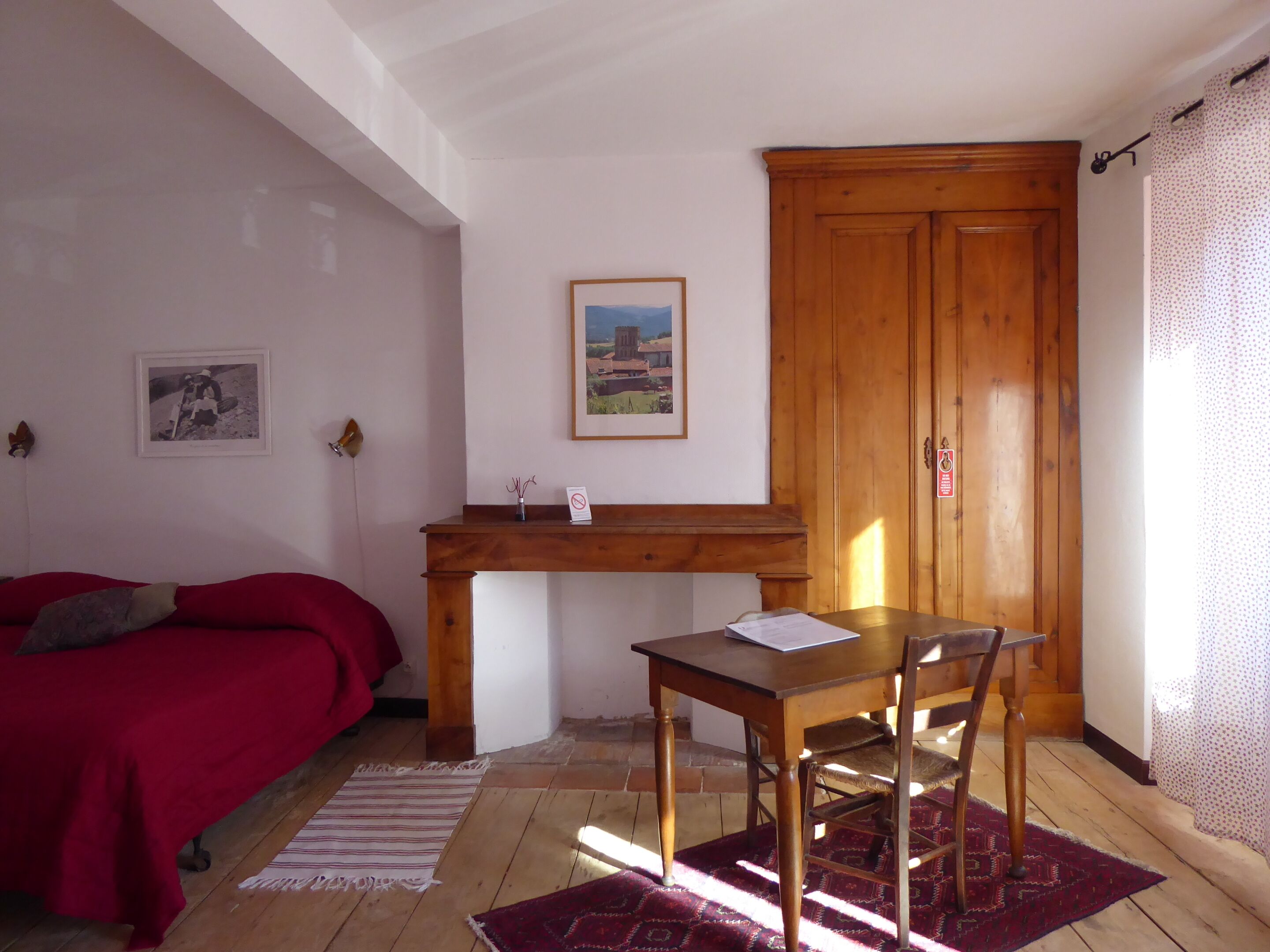 Una habitación con un escritorio de madera, un sofá rojo, un cuadro enmarcado en la pared y un armario de madera.