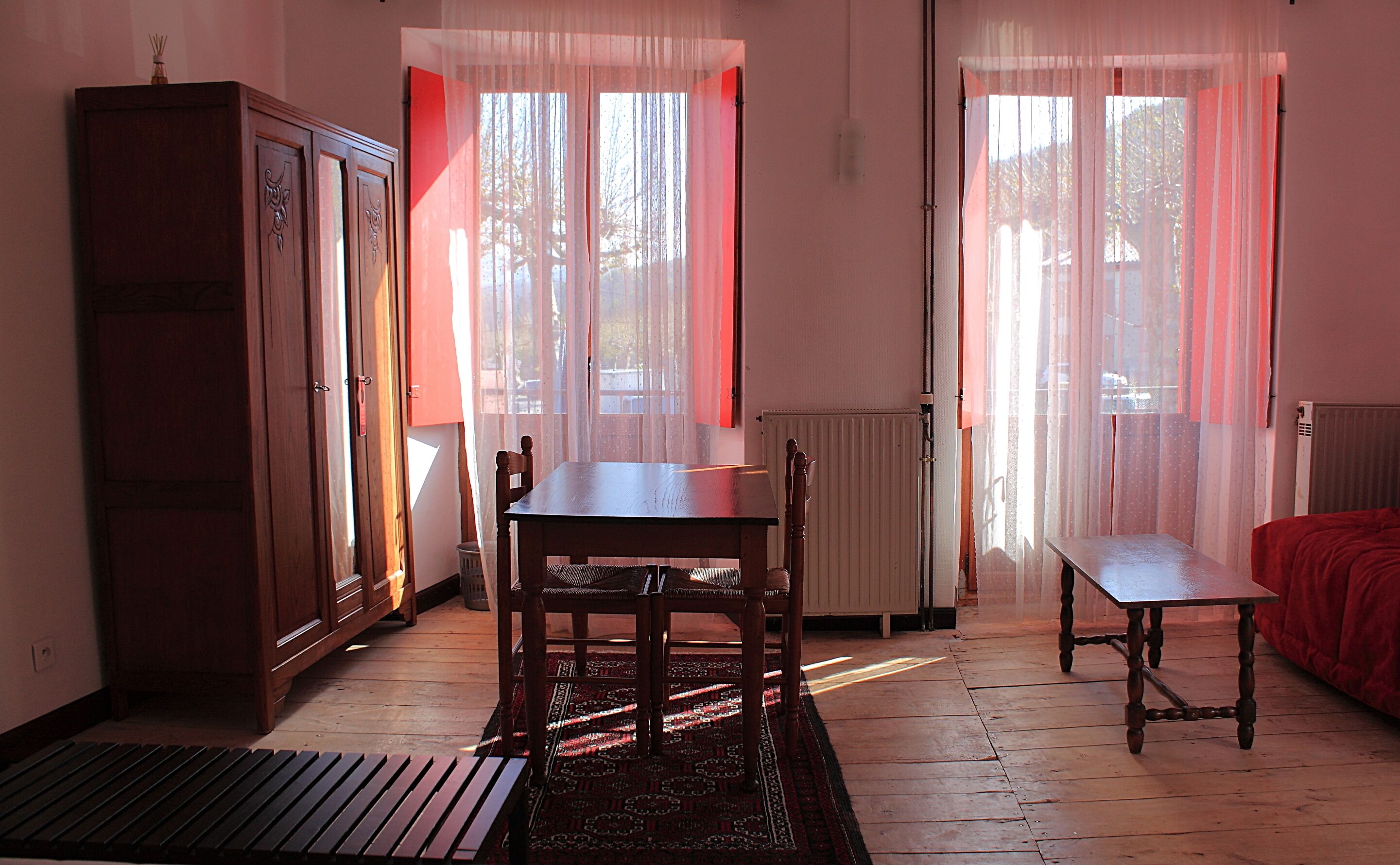 A room with a wooden table, chairs, a cabinet, and a radiator.