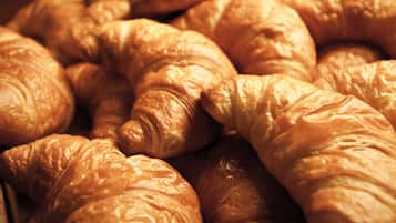 Croissants daurats i daurades amb patates exposades en caixes de fusta.