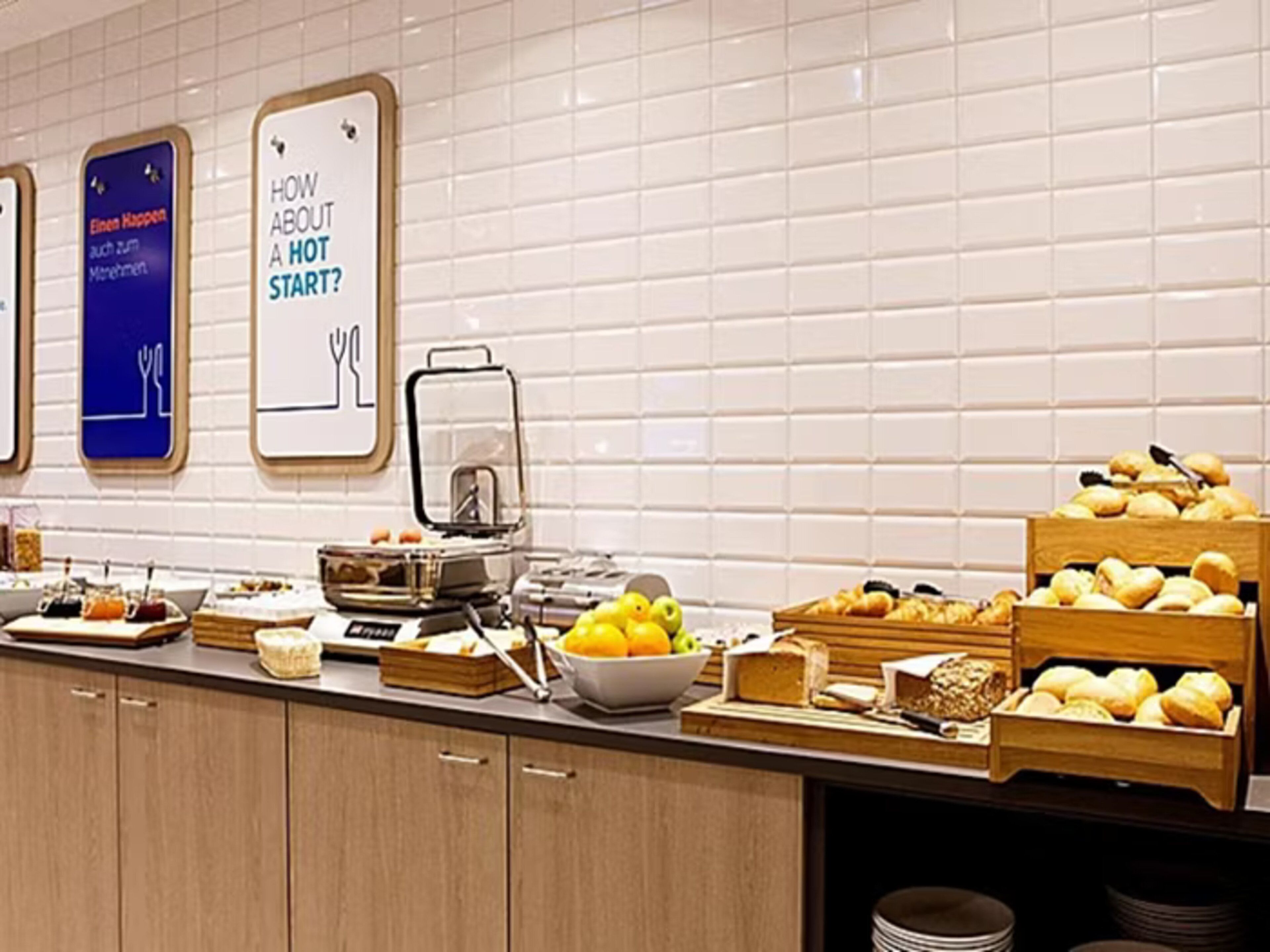 Ein reichhaltiges Buffet mit verschiedenen Speisen, einer Kaffeemaschine und einem Schild mit der Aufschrift 'Wie wäre es mit einem heißen Start?'.