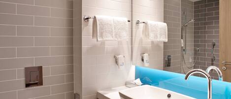 A modern bathroom with a white sink, a glass shower enclosure, and a blue accent wall.