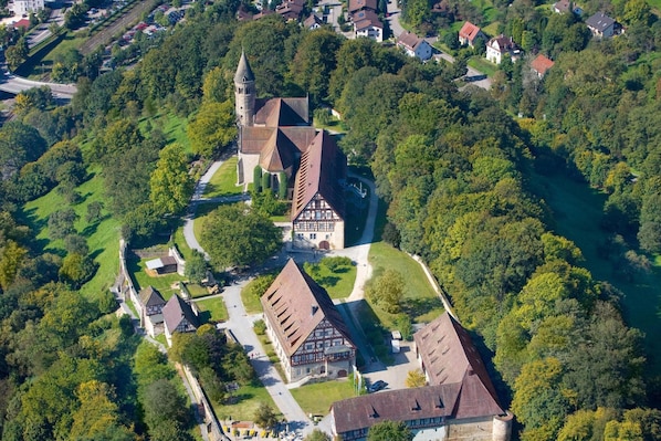 An aerial view of a historic town with a prominent church, traditional buildings, and a river.