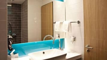 Un baño moderno con un lavamanos blanco, una bañera azul y una puerta de madera.