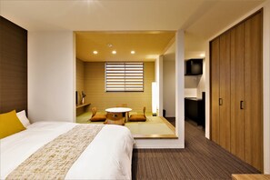 A modern hotel room with a large bed, a small round table, and a seating area with cushions. - Apartment Hotel STAY THE Kansai Airport (Izumisano)
