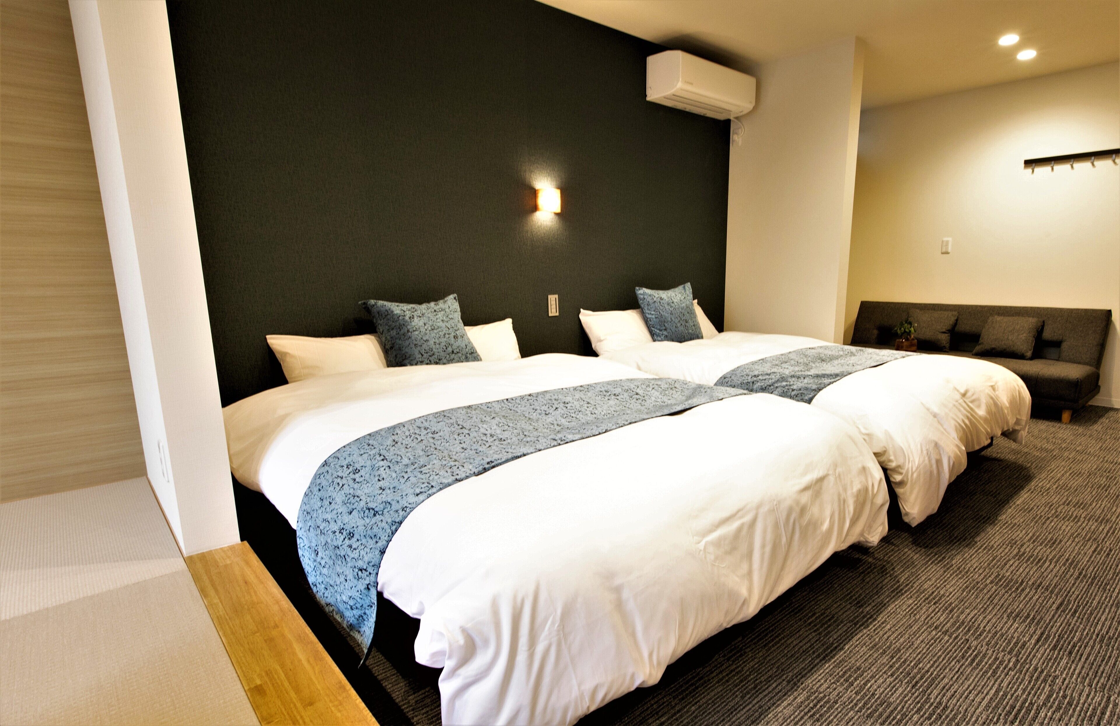 A hotel room with two beds, a dark headboard, and a small seating area with a couch.