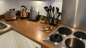 Una cocina moderna con electrodomésticos de acero inoxidable, encimera de madera y diversos utensilios.