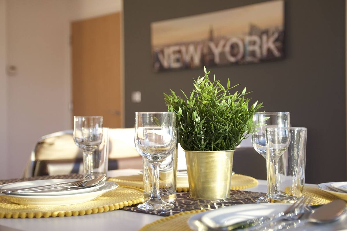 A dining table set with clear glassware, a gold-plated centerpiece, and a placemat.