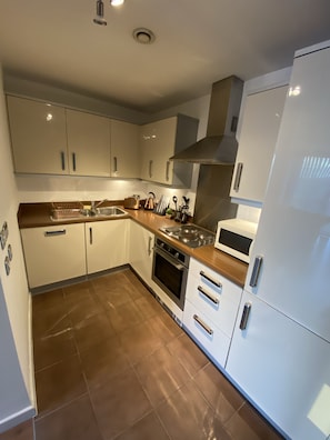 A modern kitchen with white cabinets, stainless steel appliances, and a tiled floor.