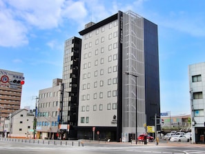 A modern hotel building with a prominent vertical design, multiple floors, and a clear sky.