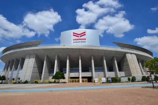 A stadium with a large, curved structure and a prominent sign reading "YANMAR STADIUM NAGAI".