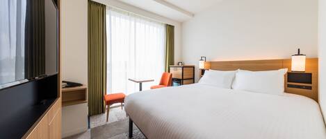 A hotel room with a large bed, a TV, a desk, and a chair.