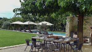 An outdoor dining area with a pool in the background, surrounded by greenery. - For rent in Drôme Provençale, an exceptional property (Grignan)