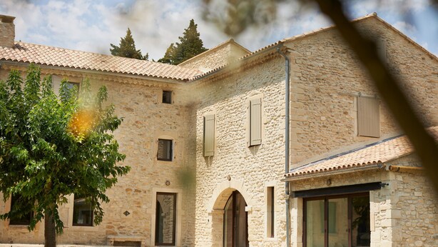 A stone building with multiple windows and doors, a tree in front, and a clear sky. - For rent in Drôme Provençale, an exceptional property (Grignan)