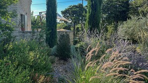 A stone building with a door and windows, surrounded by various plants and trees. - For rent in Drôme Provençale, an exceptional property (Grignan)