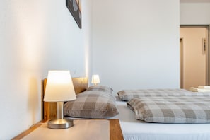Una habitació d'hotel amb un llit, dues làmpades de nit i una tauleta de nit de fusta.