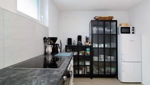A modern kitchen with a black countertop, a built-in stove, a microwave, and a refrigerator. - Apartment 'Fewo Gartenterrasse' with Private Terrace, Garden, and Wi-Fi (Meersburg)