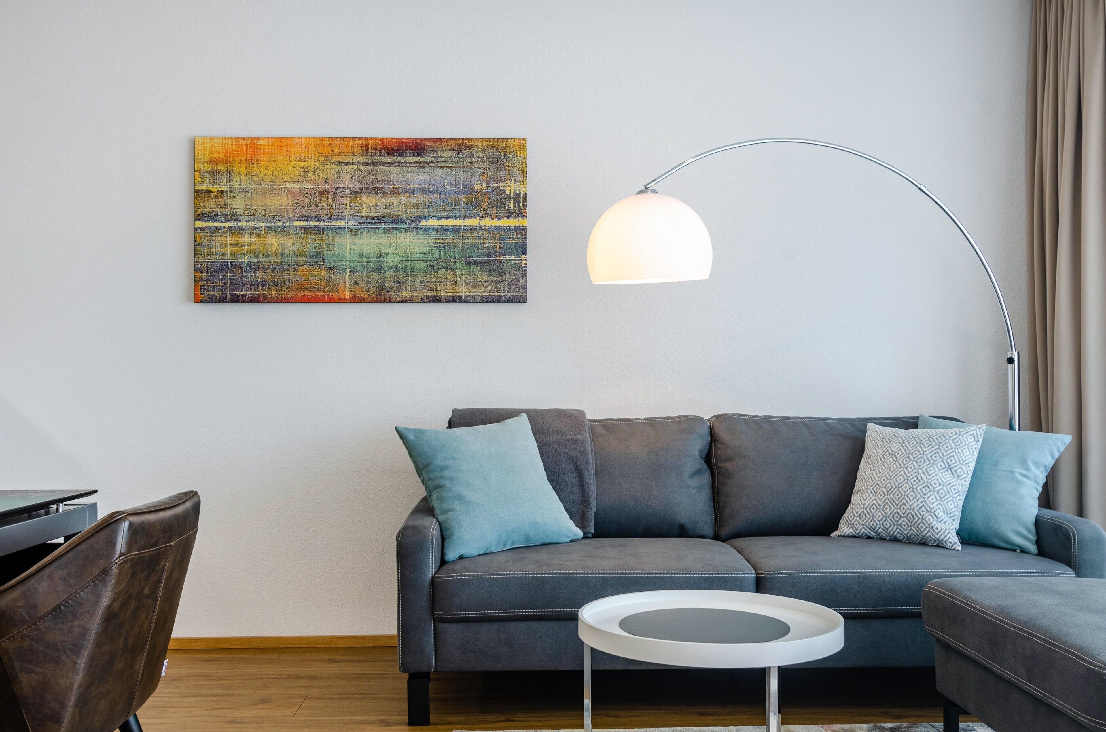 Ein modernes Wohnzimmer mit einem grauen Sofa, einem runden Couchtisch und einer Stehlampe.