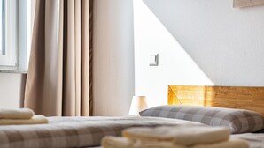Une chambre d’hôtel avec un lit, des rideaux, une lampe et une tête de lit en bois.