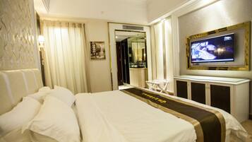 Una habitación de hotel con una cama grande, un televisor, un espejo y una mesita.