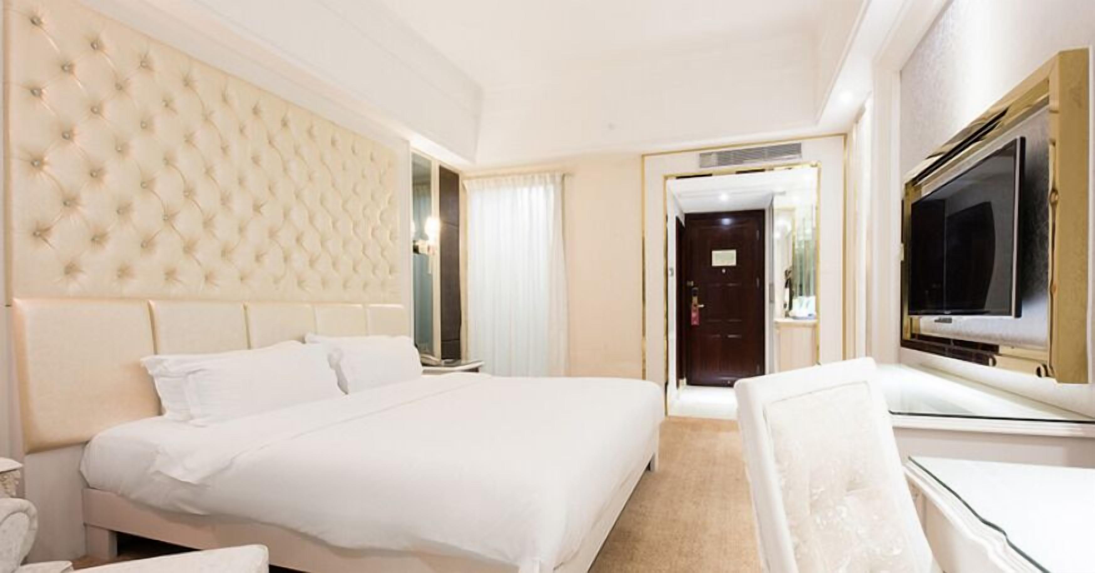 Une chambre d’hôtel avec un grand lit, une télévision et une porte donnant sur une autre pièce.