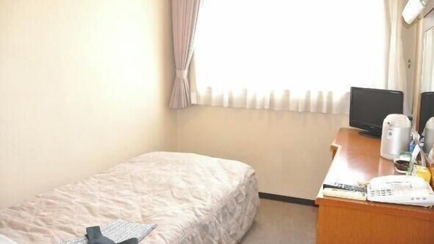 A hotel room with a single bed, a desk with a computer, a kettle, and a telephone. - Okazaki Single Hotel (Okazaki)