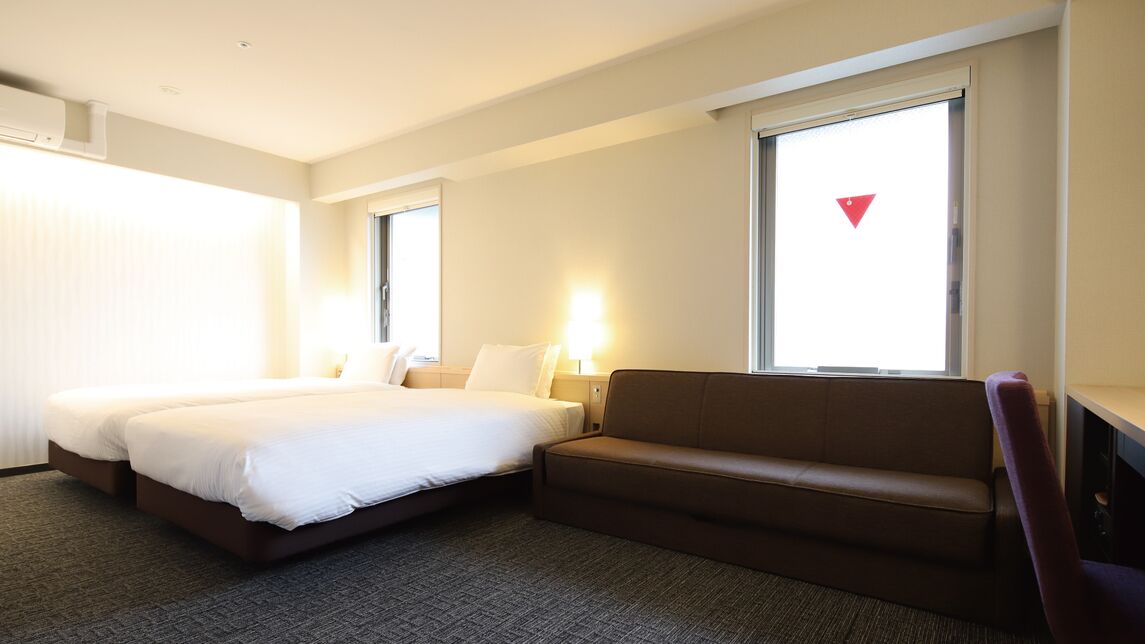 Una habitación de hotel con cama, sofá, escritorio y ventana con persianas.