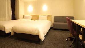 Une chambre d’hôtel avec deux lits, un bureau, une chaise et un canapé.
