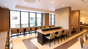 Une salle de conférence moderne, dotée d’une longue table, de chaises et de grandes fenêtres.