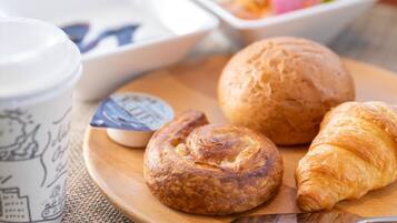A breakfast setting with a croissant, a muffin, and a cup on a wooden table.