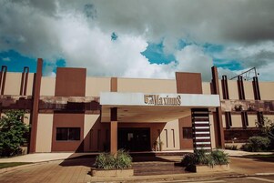 Entrada de hotel com design moderno, destacando uma placa e uma escadaria que leva à entrada.