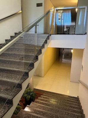 A modern interior with a glass railing staircase leading to a second floor. - Maximus Hoteis (JI PARANA)
