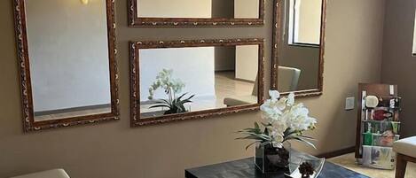 A room with a sofa, a table with a vase of flowers, and three wall-mounted mirrors.