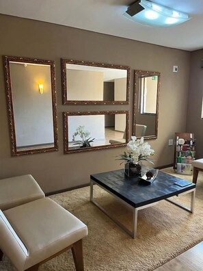 Una habitación con un sofá, una mesa con un florero y tres espejos en la pared.